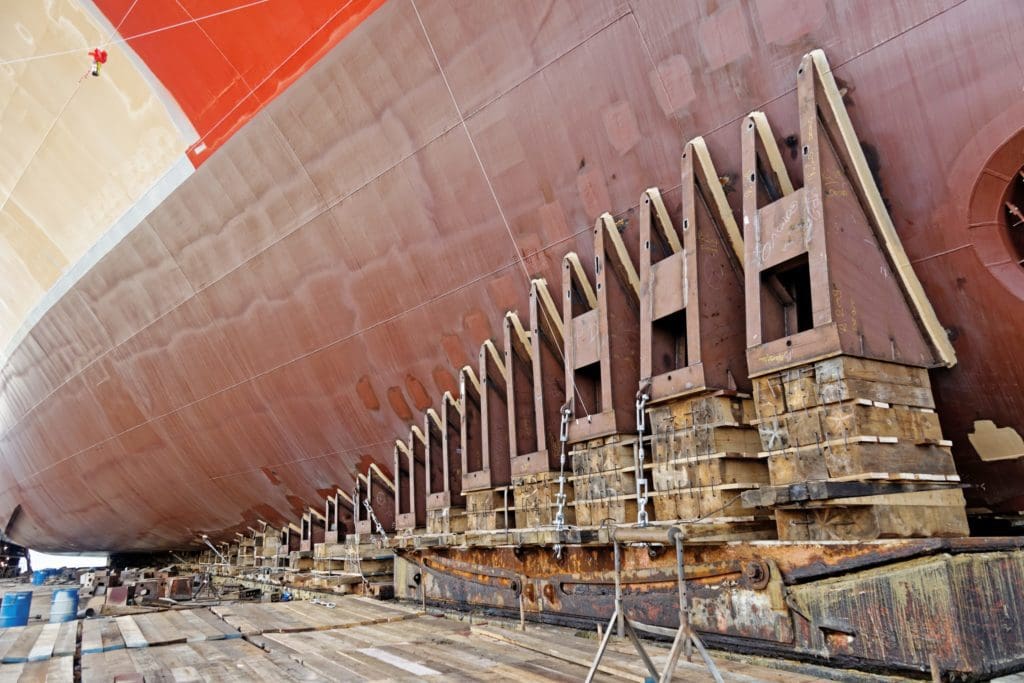 Low angle shot of a hull of ship in drydock resting on pilings ready for launch