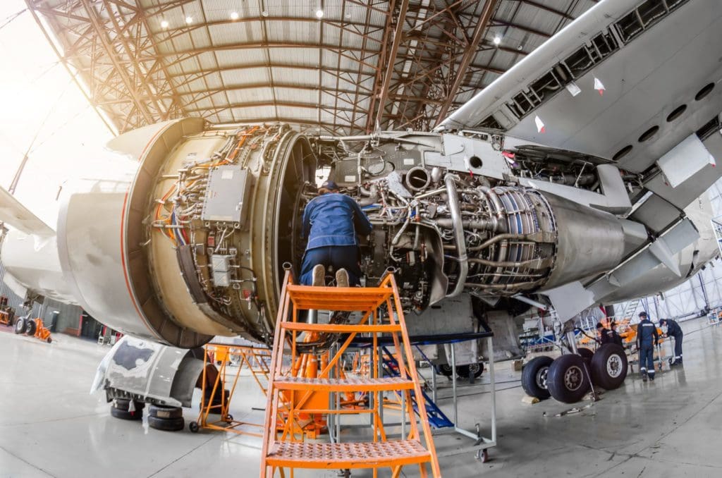 Specialist mechanic repairs the maintenance of a large engine of a passenger aircraft in a hangar