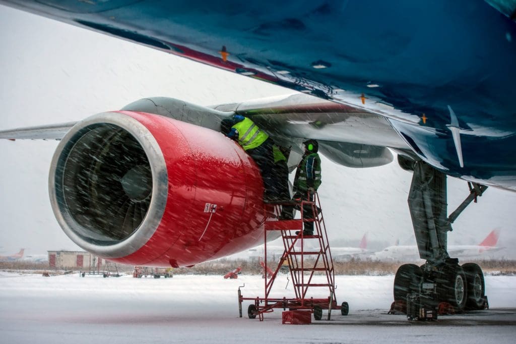 Airplane mechanics checking jet engine if civil aircraft