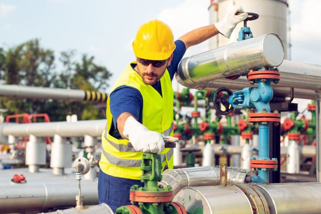 man in hard hat and yellow safety vest working on pipeline repair