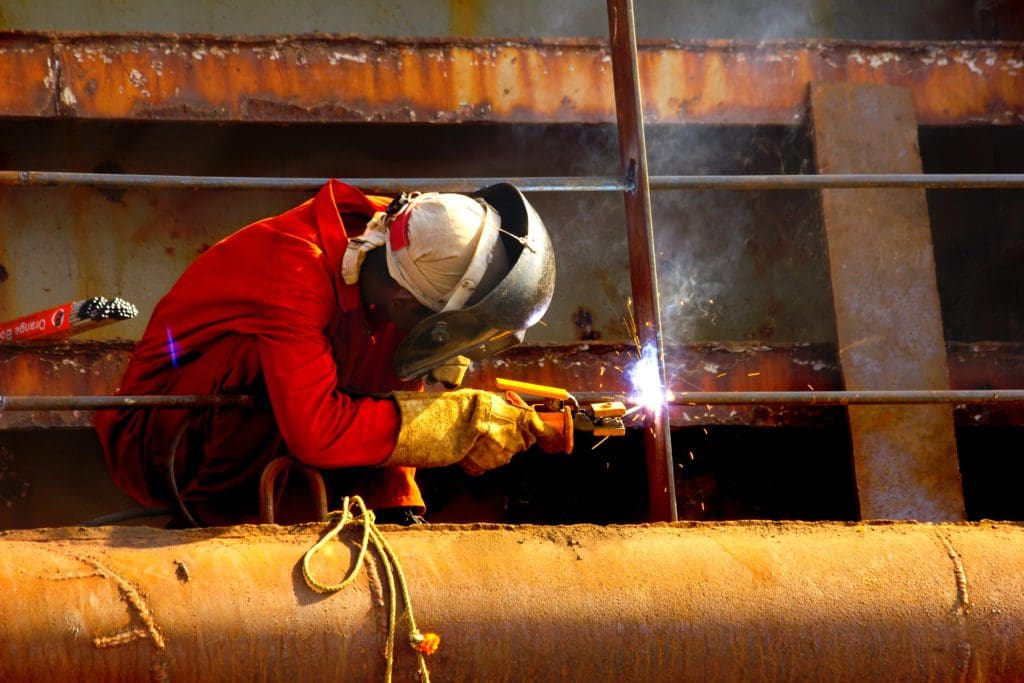 A man making ship repairs by welding.