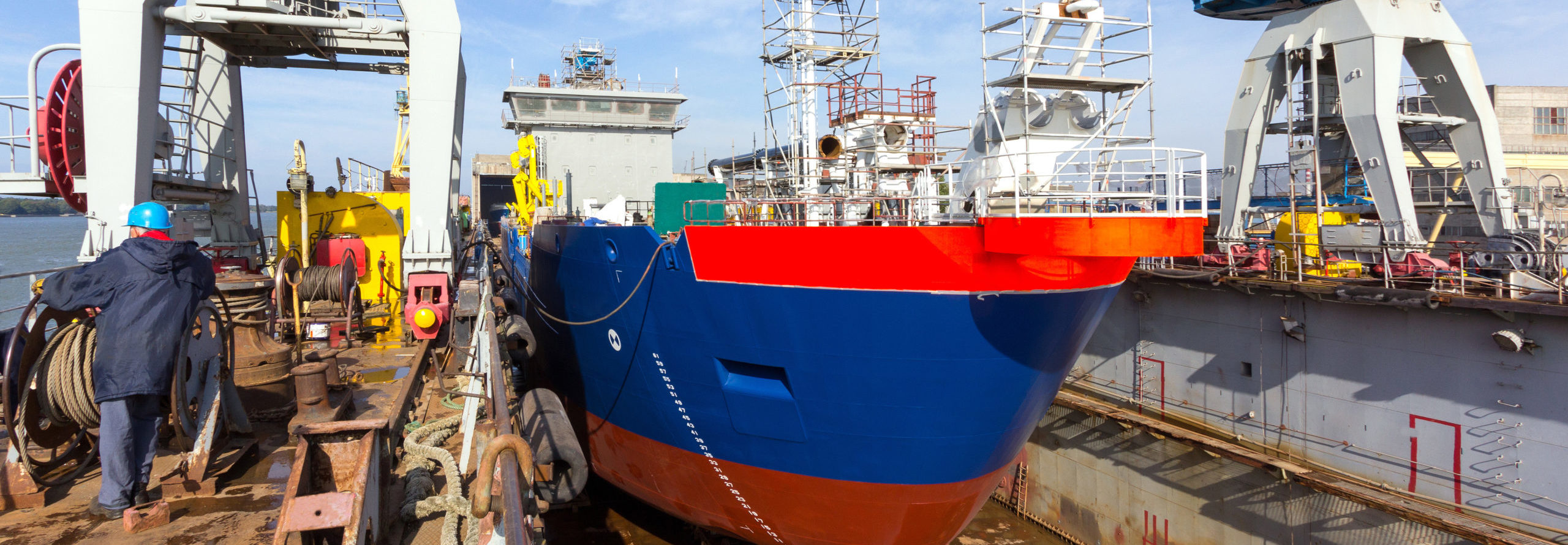 A cargo ship is building in a dock at a shipyard