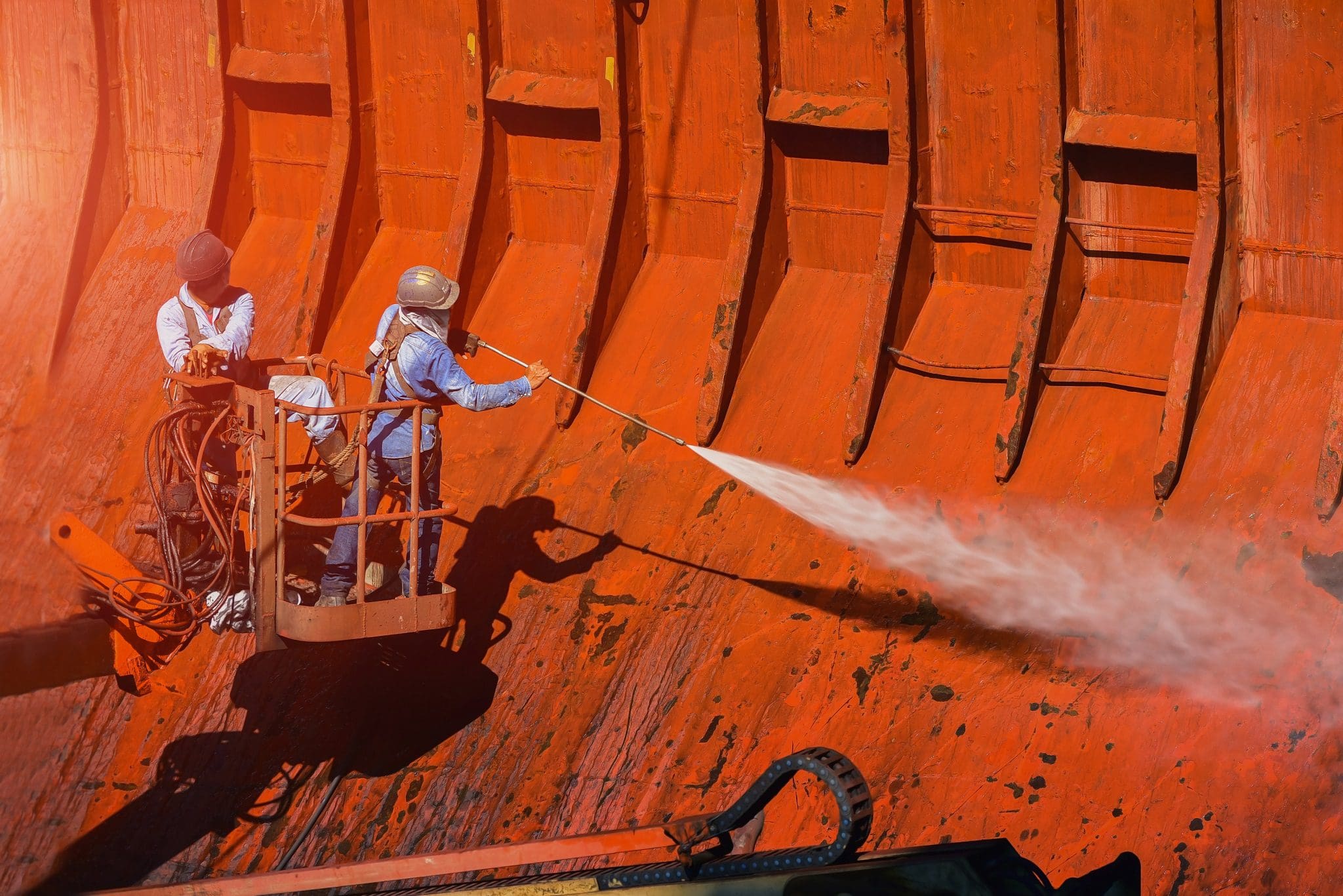 Washing and cleaning, worker High pressure water jet to cleaning with Old ship washing on Trucks have sherry piker wearing safety harness with ppe in side cargo hold under ship repair in floating dry dock in shipyard. Preparing surface for corrosion resistant coating application