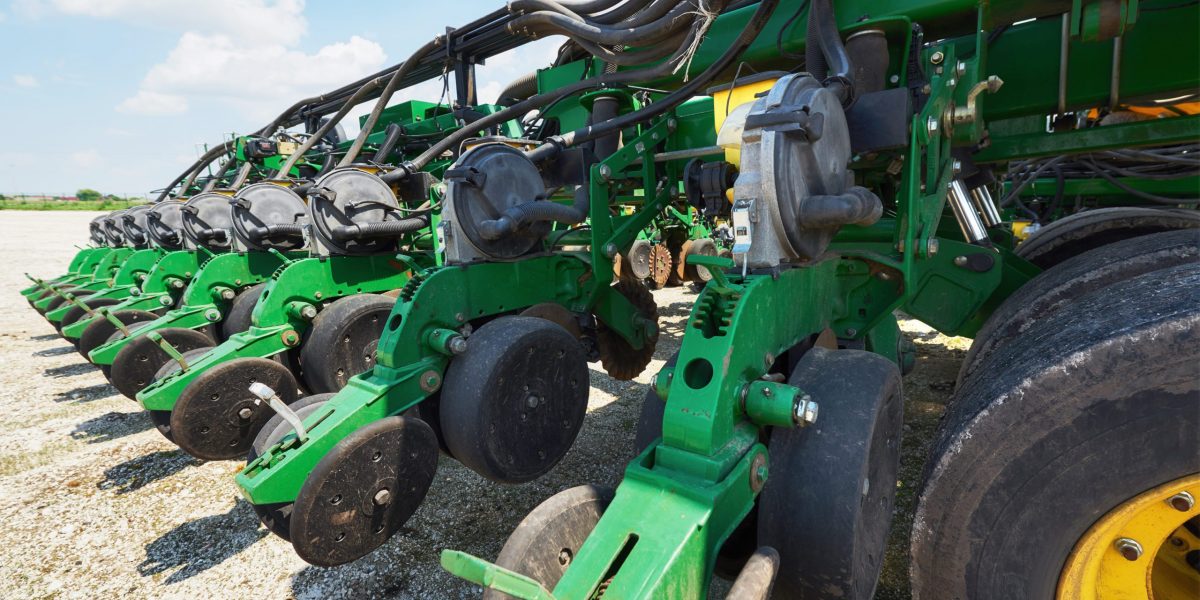 Close up of seeder attached to tractor in field. Agricultural machinery for spring works sowing