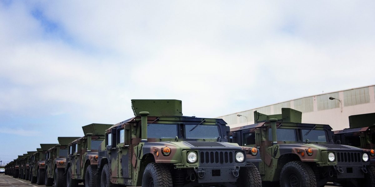 Military Vehicles Parked At Industry Against Cloudy Sky