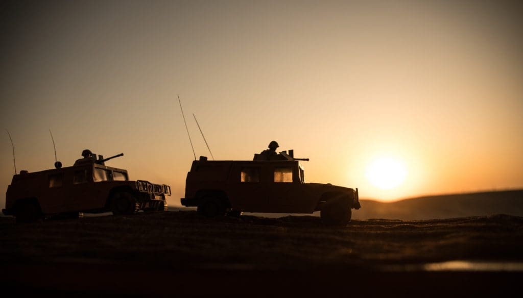 Two military vehicles travelling at dusk