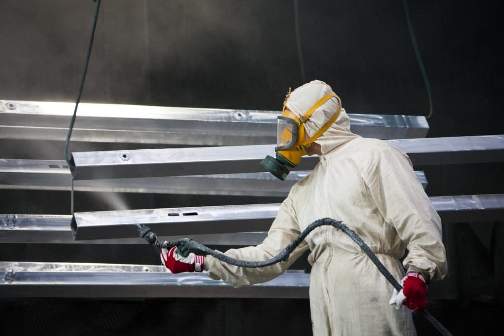 Industrial painter applying surface coating to metal